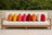 Eight colorful Sunbrella lumbar pillows on a cream teak garden sofa
